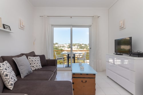Sala de estar moderna em MarVillas Rentals em Lagoa com varanda vista para o mar, sofá escuro e móveis contemporâneos