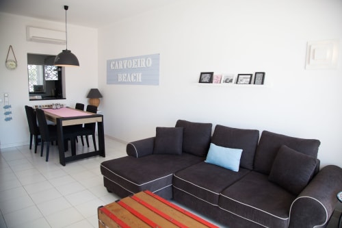 Apartamento moderno em Lagoa com sofá escuro, mesa de jantar e decoração temática praia na MarVillas Rentals