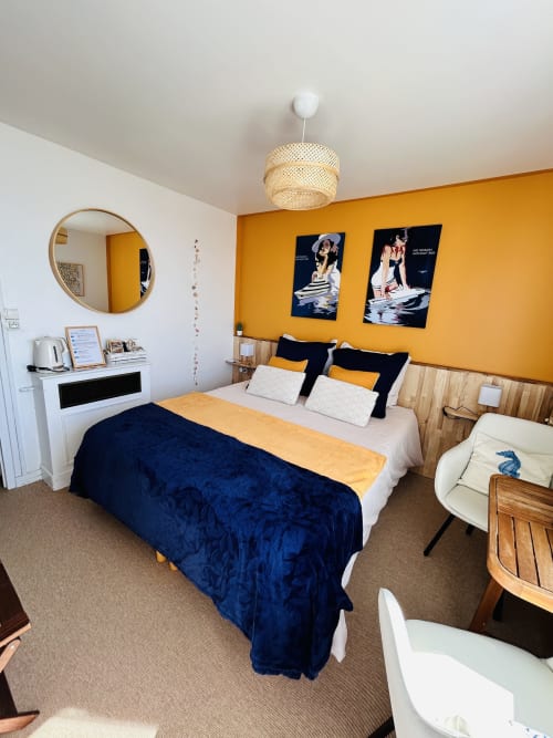 Bright bedroom with yellow walls, navy bedding, and modern décor at La Villa Plein Vent, Barneville-Carteret