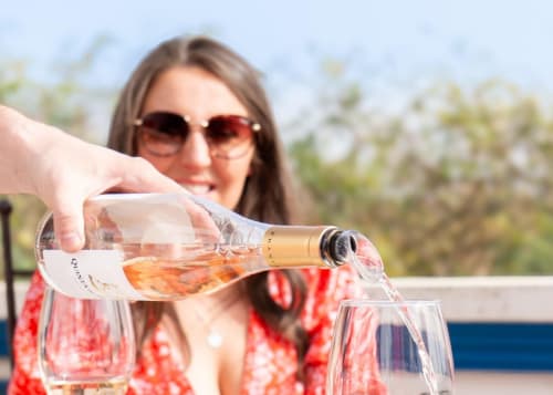 Mulher servindo vinho rosé na Luso Soul Stays em Albufeira com vista para o jardim