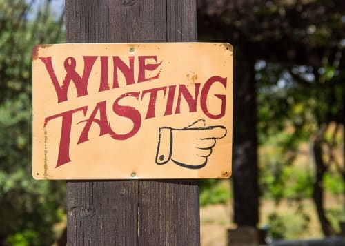 Placa vintage de degustação de vinhos apontando para a direita em poste de madeira na Luso Soul Stays em Albufeira, Portugal