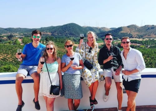 Grupo de seis hóspedes degustando vinho no terraço com vista para os vinhedos do Vale do Douro na Luso Soul Stays, Albufeira.
