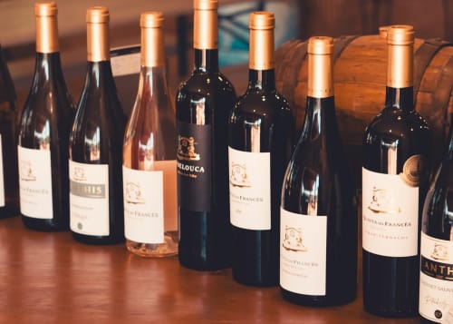 Garrafas de vinho com tampas de cobre expostas na seleção de vinhos do Luso Soul Stays em Albufeira, Portugal