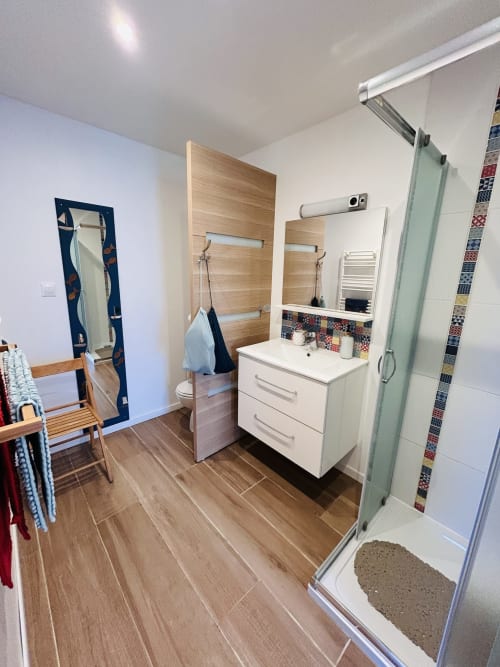 Modern bathroom in La Bounty cottage at La Villa Plein Vent, Barneville-Carteret, with white vanity, wooden accents, and