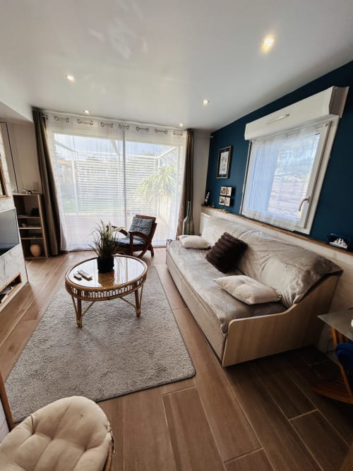 Modern cottage living room with sofa, garden view, TV at La Villa Plein Vent in Barneville-Carteret