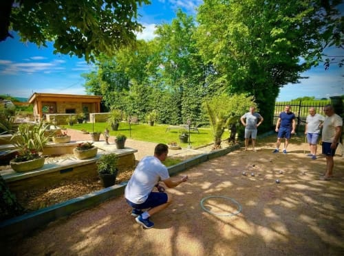 Des clients jouent aux boules dans le jardin ensoleillé du Clos Des Anges, un charmant gîte à Bagnols, France