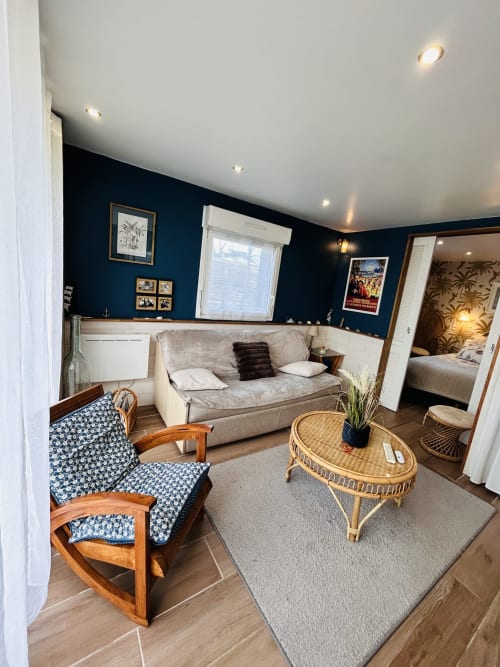 Gemütliches Wohnzimmer mit marineblauem Wandfarbton, komfortablem Mobiliar und Blick ins Schlafzimmer in La Villa Plein Vent, Barneville-Carteret