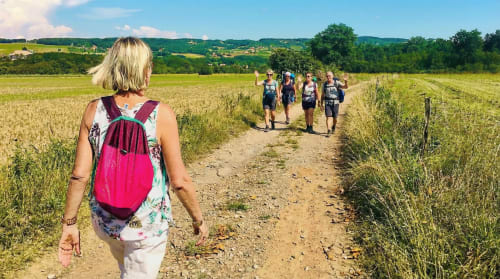 Hikers walking on rural trail near Bagnols, France with rolling countryside and vineyards in background