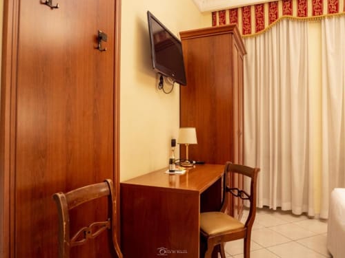 Camera matrimoniale presso Alla Basilica Rooms, San Giovanni, con scrivania in legno, sedie, TV e arredi eleganti