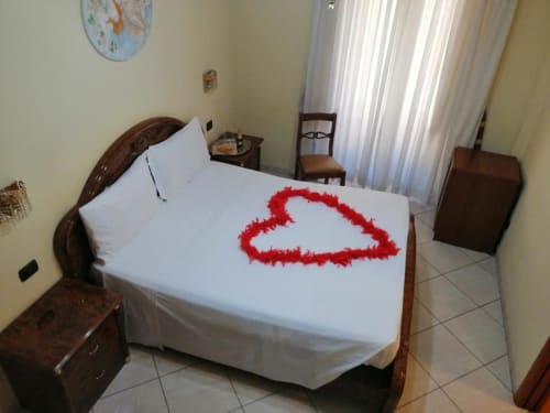 Camera matrimoniale in Alla Basilica Rooms a San Giovanni con letto bianco decorato con petali di rosa rossa