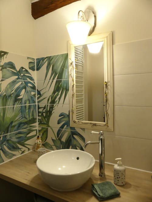Salle de bain moderne à La Cour Des Saligues avec vasque blanche, carreaux botaniques, miroir et applique murale