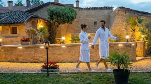Couple in robes strolling by stone courtyard at Le Clos Des Anges, a charming B&B in Bagnols, France