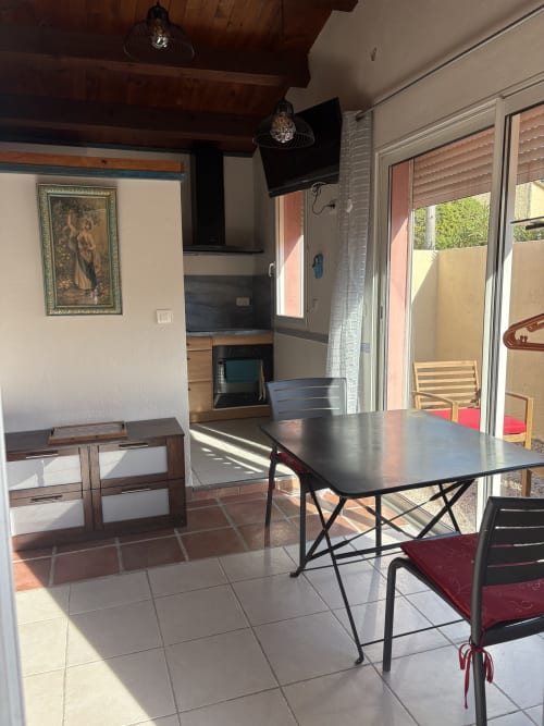 Grand Gîte cottage dining area at Casa Di Floumy in Calvi with dining table, kitchen, TV, and garden view access