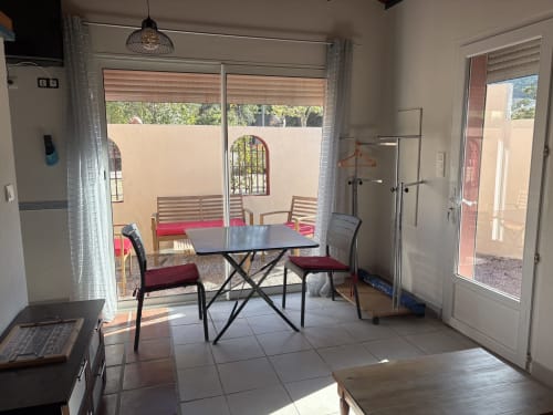 Salle à manger lumineuse du Grand Gîte de Casa Di Floumy, Calvi, avec table, chaises et vue sur le jardin par les portes vitrées