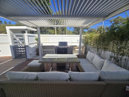 Lounge exterior moderno na villa Casa Cliff em Sesimbra com assentos trançados, pérgola e área de churrasco