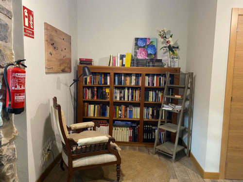 Acogedor rincón de lectura en Casa Rural Donamariako Benta con librerías de madera, sillón y estantería metálica en Donamaria
