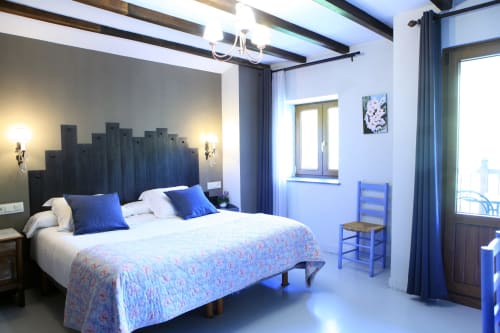 Luminoso dormitorio de villa en Casa Rural Donamariako Benta con cabecero estilo castillo azul, vistas a montañas y comodidades modernas