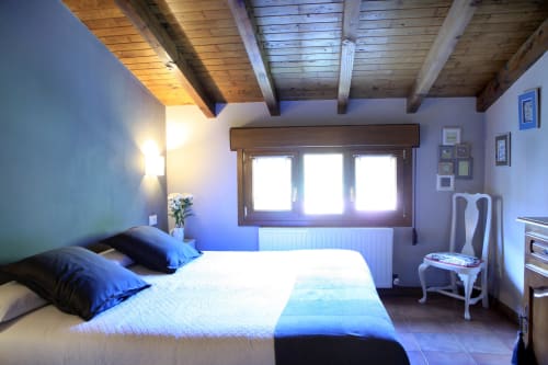 Luminoso dormitorio en la villa Casa Rural Donamariako Benta de Donamaria, con vigas de madera, amplias ventanas y vistas a las montañas