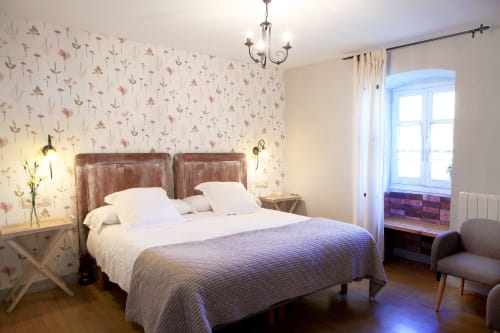 Luminosa habitación en Casa Rural Donamariako Benta de Donamaria con papel tapiz floral, cama de madera y vistas a las montañas