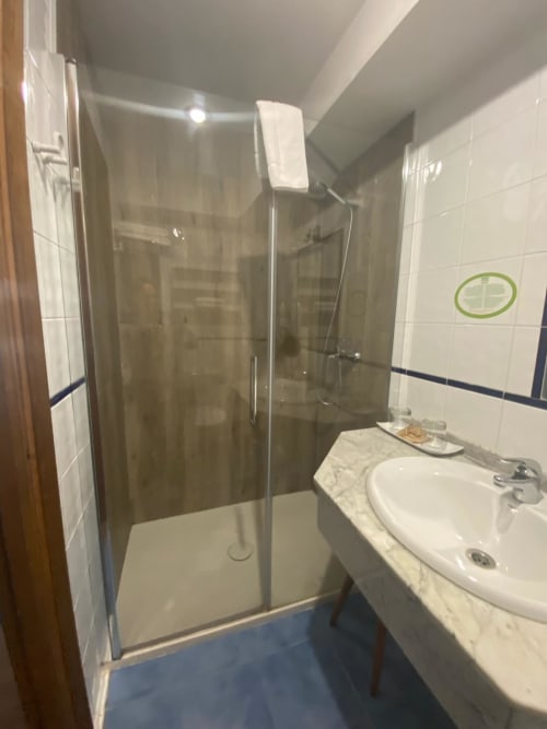 Moderno cuarto de baño con ducha de cristal y lavabo blanco en Casa Rural Donamariako Benta en Donamaria, España