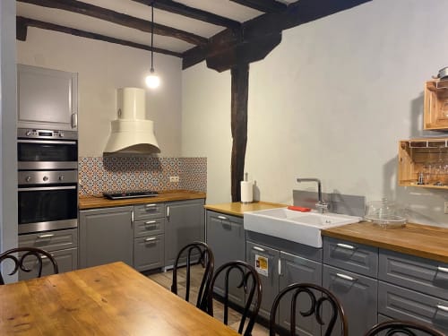 Cocina moderna con muebles grises, encimeras de madera y azulejo decorativo en el salpicadero de Casa Rural Donamariako Benta