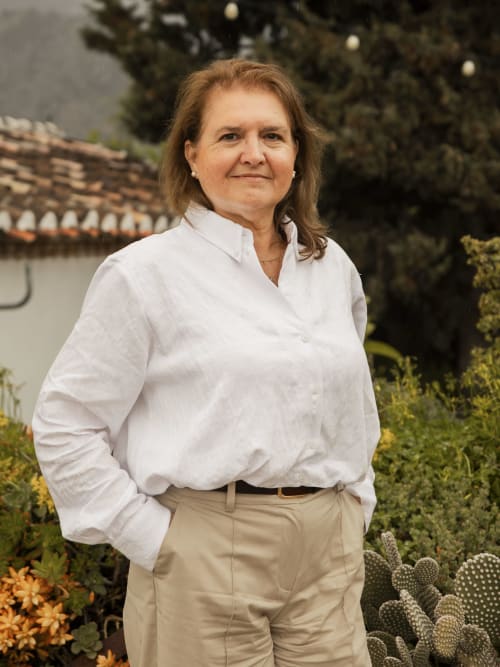 Mujer con camisa blanca de pie en el jardín del hotel Escanda Building Solutions en España