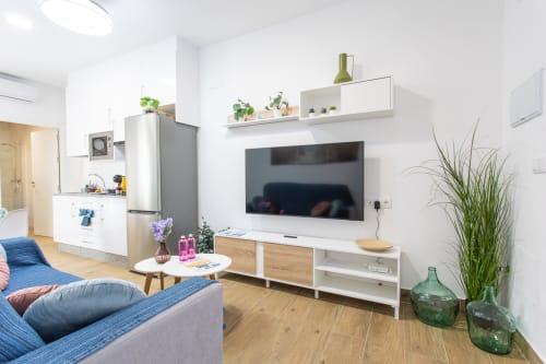 Sala moderna con televisor, muebles de madera y plantas en Casa Libertenio, Los Alcázares, España