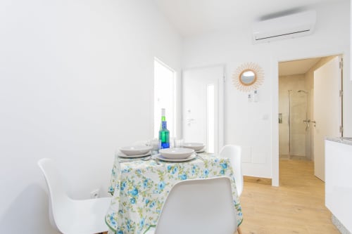 Comedor luminoso en Casa Libertenio Los Alcázares con mesa redonda, mantel floral y entrada a cocina moderna