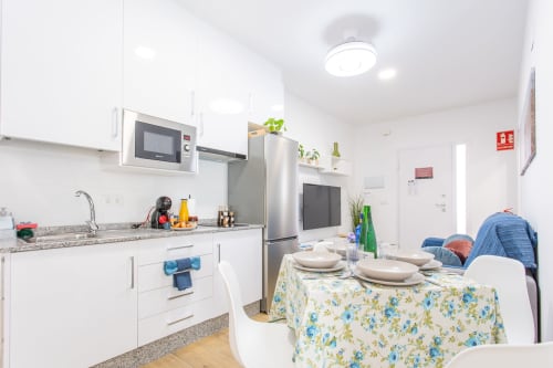 Cocina y comedor modernos y luminosos en Casa Libertenio, Los Alcázares con muebles blancos, electrodomésticos de acero inoxidable