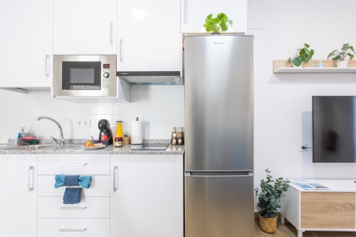 Cocina moderna en Casa Libertenio, Los Alcázares con refrigerador acero inoxidable, microondas, armarios blancos y granito