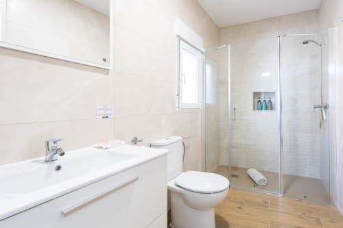 Baño moderno con vanitory blanco, inodoro y cabina de ducha de cristal en Casa Libertenio, Los Alcázares