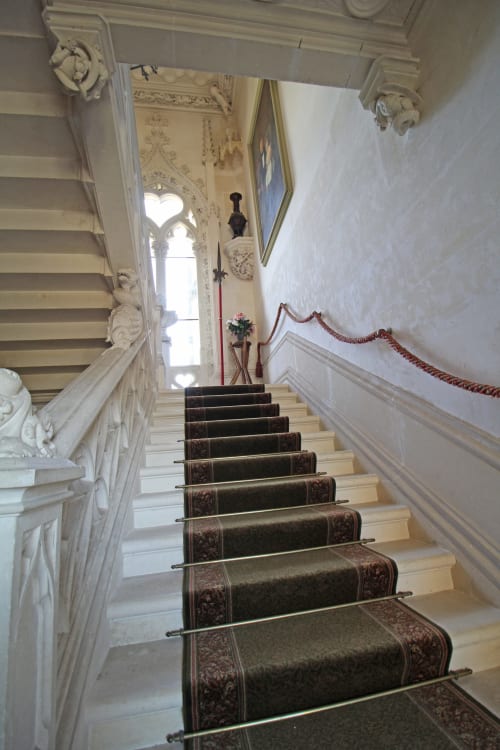 Grand staircase with dark patterned carpet runner in historic château at Domaine de Bort near Limoges, France