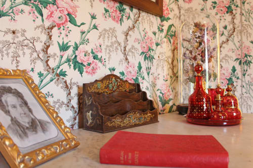 Historic bedroom with floral wallpaper, red candles, gilt frames, and period furnishings at Domaine de Bort near Limoges