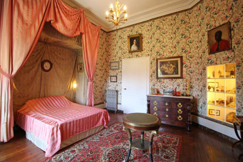 Chambre luxueuse avec lit à baldaquin rose, papier peint fleuri et mobilier d'époque au Domaine de Bort près de Limoges