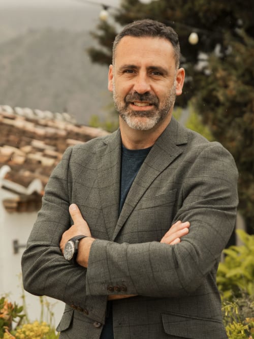 Hombre profesional con blazer gris de pie en el exterior del hotel Escanda Building Solutions en España