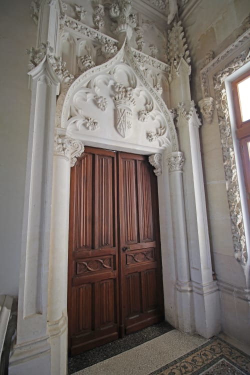 Ornate white plasterwork frames a wooden double door at Domaine de Bort historic property near Limoges, France