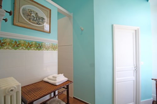 Turquoise bathroom with white tile, decorative border, and towels at Domaine de Bort near Limoges, France
