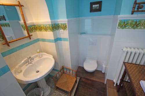 Bathroom at Domaine de Bort B&B with turquoise tile details, pedestal sink, toilet, and radiator