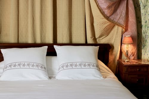 Elegant bedroom at Domaine de Bort with white pillows, cream drapes, and wooden furniture near Limoges
