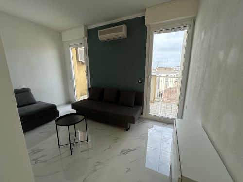 Moderno loft all'hotel Anthea a Lignano Sabbiadoro con divano nero, pavimenti in marmo, balcone e vista sullo skyline della città