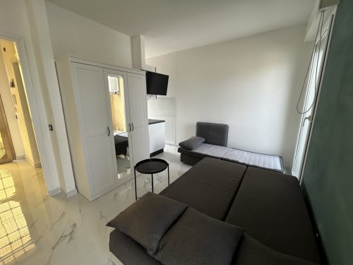 Moderno monolocale all'Anthea Hotel di Lignano Sabbiadoro con divano scuro, angolo cottura, armadio e TV