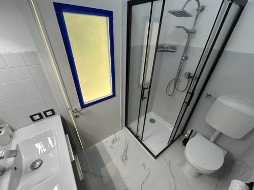 Bagno moderno nell'appartamento Anthea Loft Harmonia a Lignano Sabbiadoro, con cabina doccia, wc e specchio illuminato