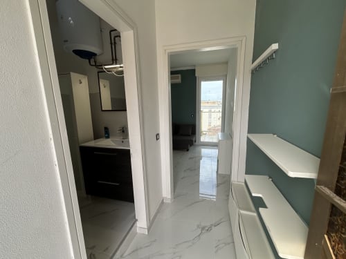 Moderno corridoio di appartamento a Lignano Sabbiadoro con pavimenti in marmo, bagno, angolo cottura e scaffali con vista sulla città