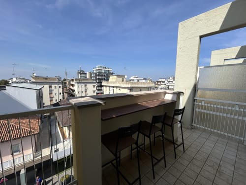 Area bar sul tetto dell'hotel Anthea a Lignano Sabbiadoro con posti a sedere, vista sulla città e lo skyline