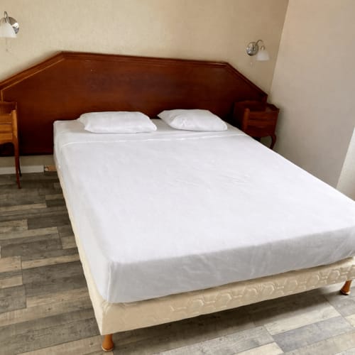 Hotel de Champagne double bedroom with wooden headboard, white bedding, and two pillows in Saint-Dizier