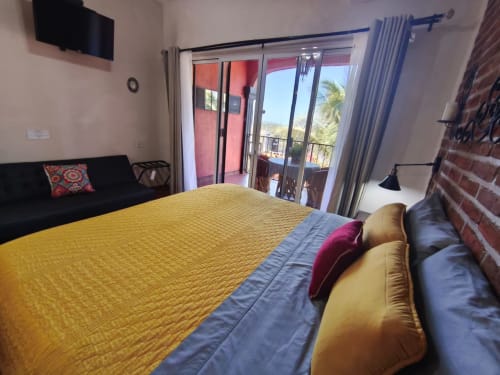 Dormitorio luminoso en villa de Punta Perula con ropa de cama amarilla, balcón con vistas al mar y comodidades modernas