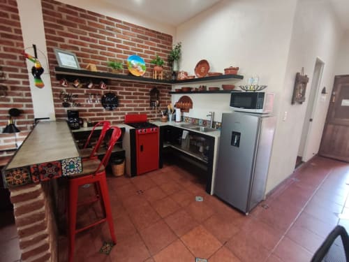 Moderna cocina de la villa Casa Punta Perula con acentos rojos, electrodomésticos de acero inoxidable, estantes de ladrillo y comedor