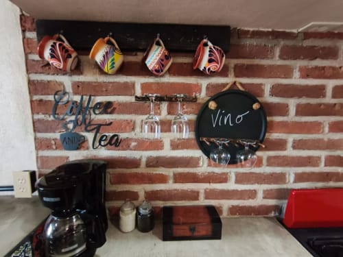 Área de cocina con tazas decorativas coloridas, cafetera y cartel de vinoteca en la villa Casa Punta Perula en Punta Perula,