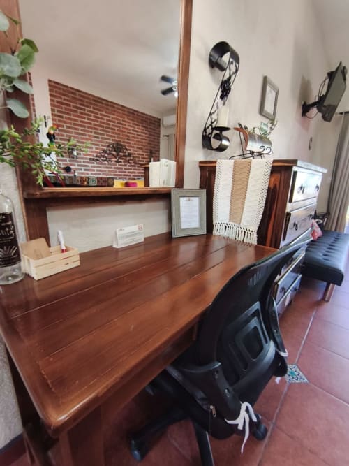 Espacio de trabajo de oficina en casa con escritorio de madera, silla negra, pared de ladrillo y decoración de villa costera en Casa Punta Perula