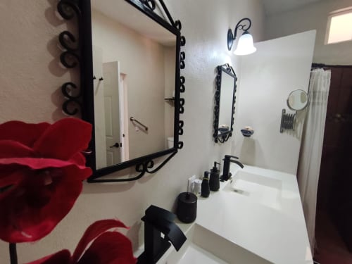 Baño moderno con espejo ornamental negro, tocador blanco y acabados en negro en Casa Punta Perula, boutique hotel en Punta Perula